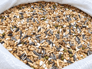 Close-up of dry sprouting seed mix for birds inside an open woven bag.